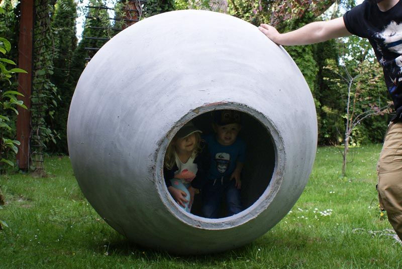 Dzieci we wnętrzu betonowej kuli ogrodowej