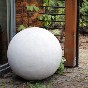 Kula betonowa gładka o naturalnym wyglądzie pusta w środku z lekkiego betonu ustawiona w altanie przy domu